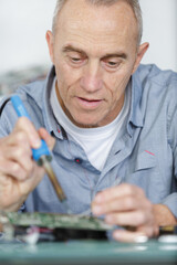 mature man soldering a pc board