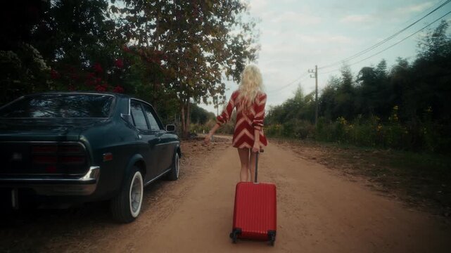 Blonde Woman In Retro Attire By Automobile. Serene Woman Resting Near Vehicle Amidst Lush Flowers