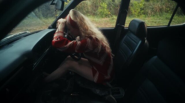 Blonde Woman In Retro Attire By Automobile. Serene Woman Resting Near Vehicle Amidst Lush Flowers