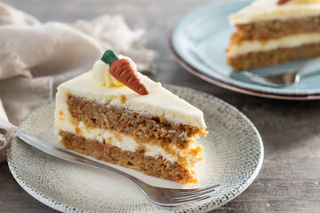 Carrot cake slice with cream cheese frosting on wooden table
