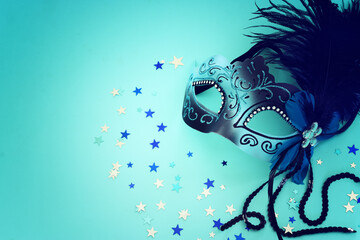 Holidays image of masquarade mask over blue background. view from above
