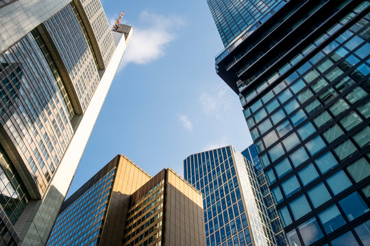 Looking upward between modern glass skyscrapers in Frankfurt Bankenviertel corporate district with clean facade detail and open blue sky