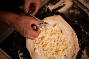 Hands slicing blue cheese for homemade pizza
