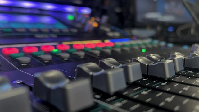 Close-up of an audio mixing console with moving faders and blinking lights during live event production. Professional sound engineering workflow in an event and broadcast environment.