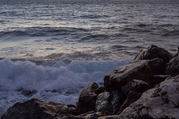 Moody sunset over the sea with textured waves and warm light reflecting on the water. Natural coastal scene conveying tranquility, power, and evening atmosphere in Athens.