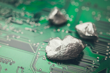Mineral rare earth element on green electronic circuit board background copy space. US vs China chip war, tech war, semiconductor industry concept. China curbs on exports of rare earth element to US.