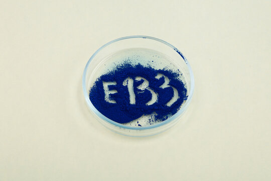 Food additive E133. Brilliant blue FCF, dye powder in glass Petri dish. Triarylmethane dye known also as Atracid Blue FG. Pigment part of creams, shampoos and other cosmetic products