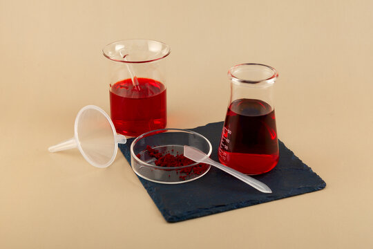 Experiments with food coloring E129. Red dye powder dissolved in water in laboratory glassware in various concentrations. Allura Red AC, azo dye commonly used in cosmetics, drugs, drinks and food
