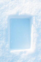 Rectangular imprint on the fluffy, snowy surface with sunlight.