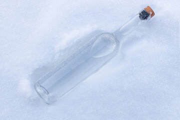 Glass bottle in the fluffy, white, snowy surface.Cold vodka concept.
