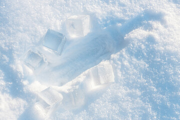Imprint from the bottle on the fluffy, snowy surface with sunlight surrounded by ice cubes.