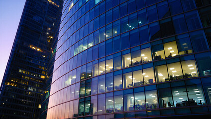Modern Office Building Exterior at Dusk with Illuminated Windows and Blue Glass Facade ©  Blar Studio