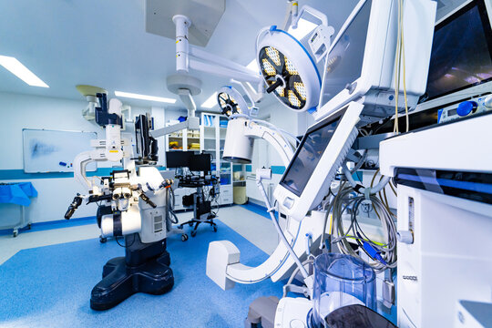 Neurosurgical operating room with surgical microscope and mobile C-arm system. Spacious surgical suite containing advanced neurosurgery microscope, C-arm imaging, and anesthesia equipment.