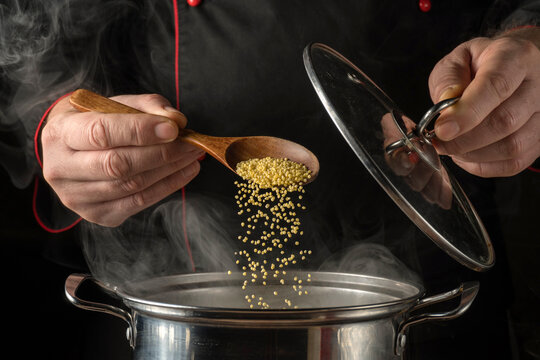 Chef adds grains Panicum to pot while cooking in a kitchen during a meal preparation session