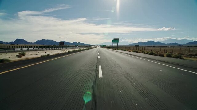 Moving cam filming forward as vehicle driving along desert road showing dashed centerline and sign