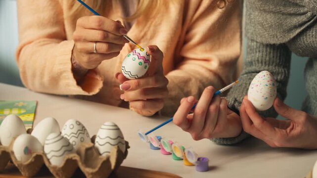 Close up of hands painting decorative patterns on Easter eggs, festive pastel traditions