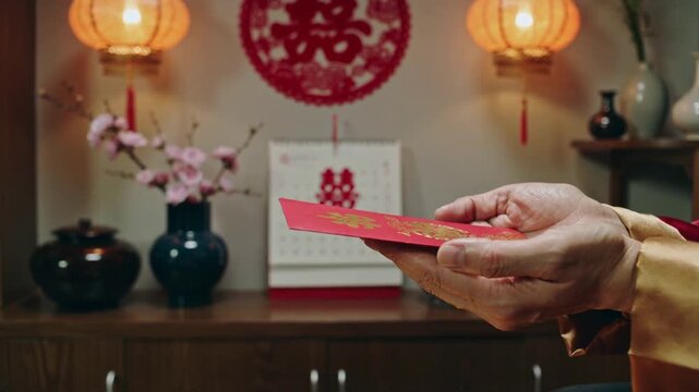 Passing maroon-sleeved hand meeting red-gold cuff, exchanging red envelope at home celebration