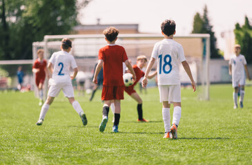 Obraz premium Youth Soccer Match Near Goal; Young Football Players Walking on Grass Field