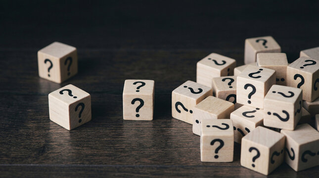 A pile of wooden blocks with question marks on them scattered across a dark wooden surface