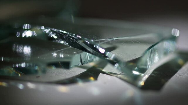 Lighting shifting, sequence showing stacked glass shards on counter, revealing splinters and bokeh