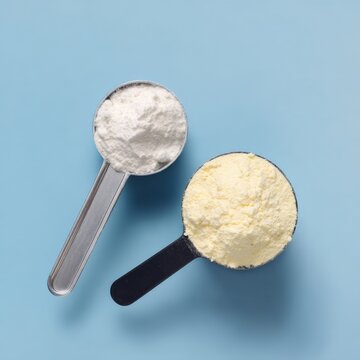 Two measuring cups with white and yellow powder on blue background