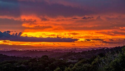 Obraz premium Fiery sunset over rolling hills with colorful cloudscape panorama and peaceful atmosphere for nature beauty.