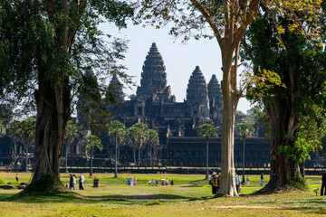 Angkor Wat, Cambodia, the temple, seen through trees with many tourists.