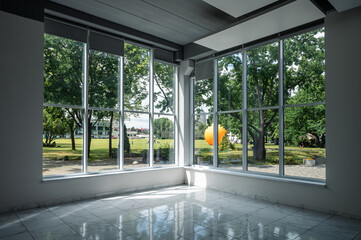 Empty modern room with large windows and park view in daylight