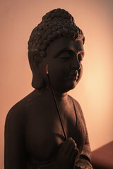 Tranquil Buddha statue with glowing incense stick in soft candlelight for meditation and spiritual harmony