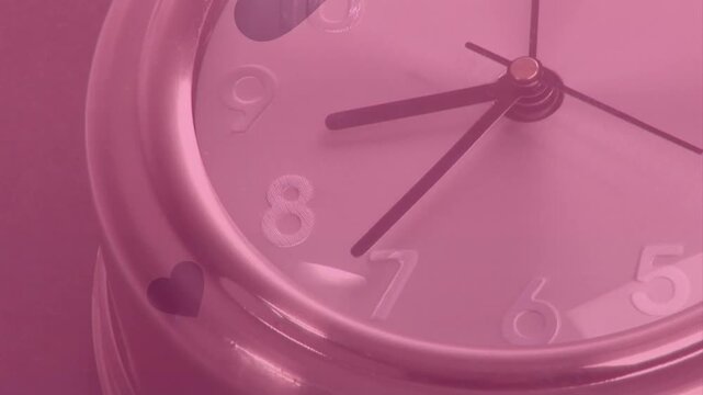 Hearts appearing on round chrome alarm clock after pause, drifting across pink dial forming overlay