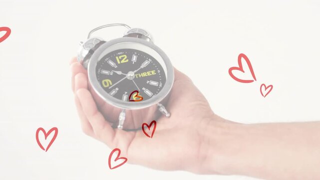Hand entering from right holding silver clock causing red hearts rising drifting highlighting clock
