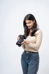 young indian woman holding digital camera standing on white background