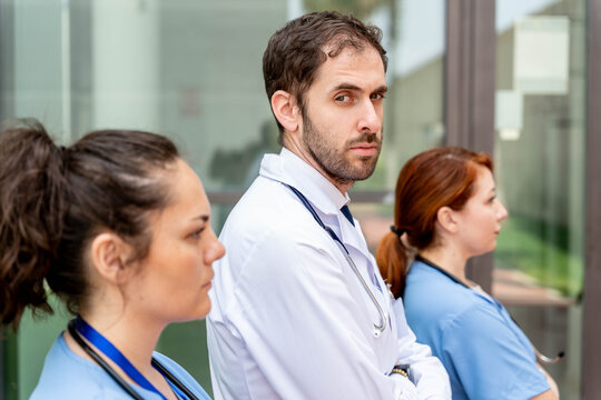 Healthcare professionals standing together, including a doctor looking seriously, representing healthcare professionals and frontline workers