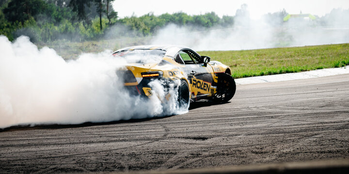 yellow Toyota GT86 drift car exiting a turn with smoke. Dynamic rear-angle shot of a modified sportscar as it slides through a corner on an asphalt track. Chaiky, Ukraine - August 02 2025