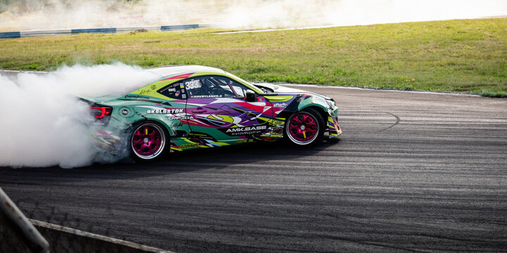 Colorful Toyota GT86 drift car sliding in a turn with smoke. Dynamic side shot of a modified sportscar as it slides through a corner on an asphalt track. Chaiky, Ukraine - August 02 2025