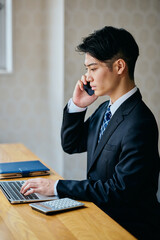 Businessman Talking on Smartphone While Working on Laptop in Office
