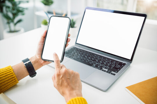 Asian business woman using mockup smartphone and laptop at home office concept of digital multitasking remote communication technology synchronization and modern online business productivity