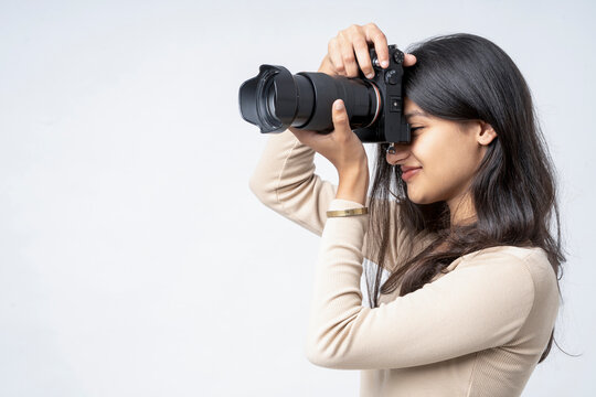 young indian woman holding digital camera standing on white background