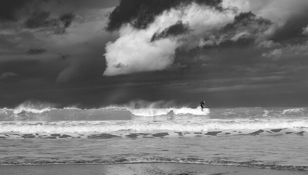 Black and White photo of surfers surfing the waves under stormy skies in Cornwall 