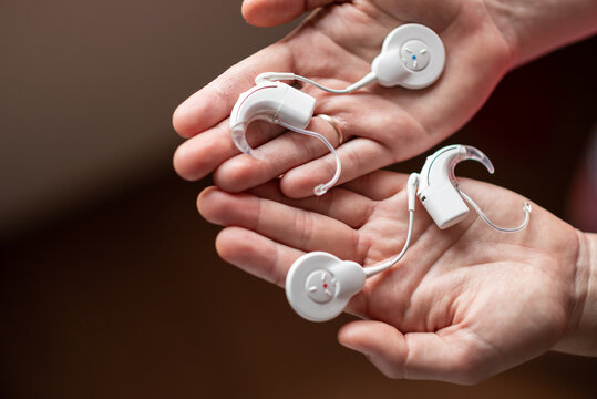 Modern cochlear implant devices resting in open hands. Advanced medical technology for people with severe hearing loss. Audiology, hearing rehabilitation and healthcare concept. Assistive technology 
