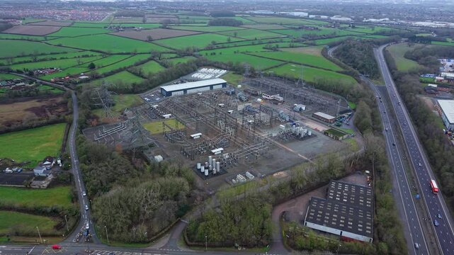 Aerial drone view of a massive electrical substation featuring high voltage transformers and switchgear for the Great Grid Upgrade UK.