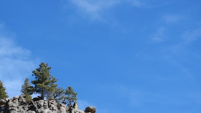 4K winter clouds drifting over rocky mountain ridge with pine trees, Colorado