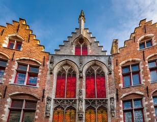 Obraz premium gothic style brick facade of a historic building in bruges belgium featuring arched windows with colorful stained glass and architectural details typical of the flemish medieval heritage