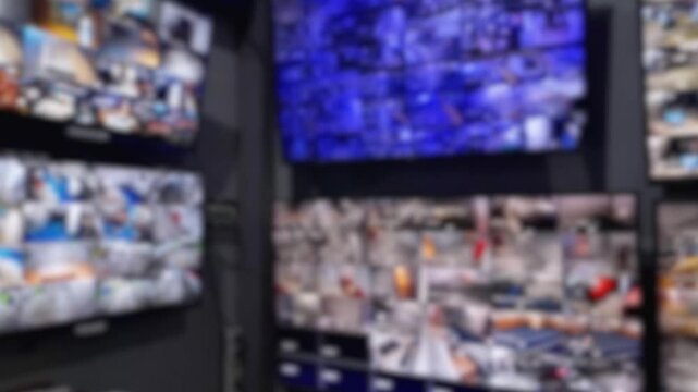 Blurred CCTV surveillance monitors displaying multiple security camera feeds in control room. Concept of video monitoring system, security operations center, protection, safety, and technology
