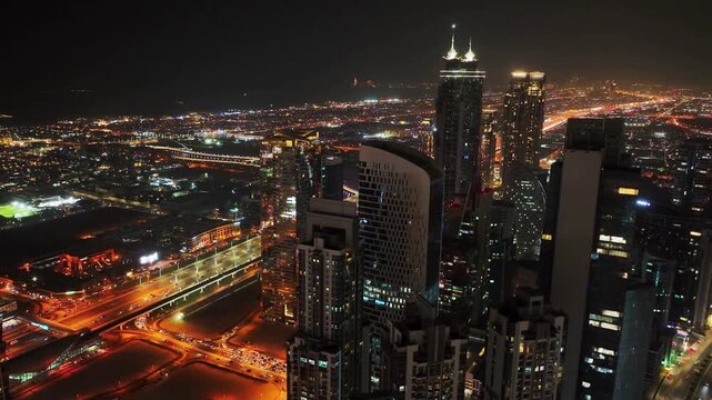 Cinematic drone shot of Downtown Dubai at night revealing skyline buildings, luxury hotels and properties with illuminated highways and Business center 