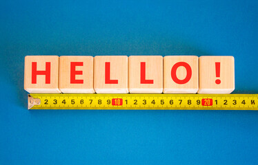 Fototapeta premium Hello welcome support help symbol. Concept word Hello on beautiful blocks. Beautiful blue background. Beautiful yellow tape measure ruler. Business psychological hello support help concept Copy space