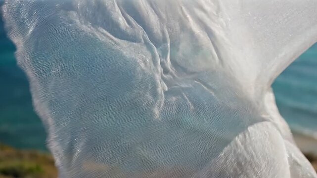 A video showcasing a white sheet blowing in the ocean breeze