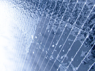 Extreme close-up of ice and frost patterns on a blue solar panel in winter.