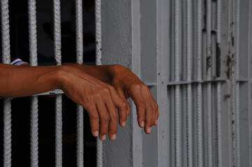 Obraz premium prisoner's hands behind bars at black background