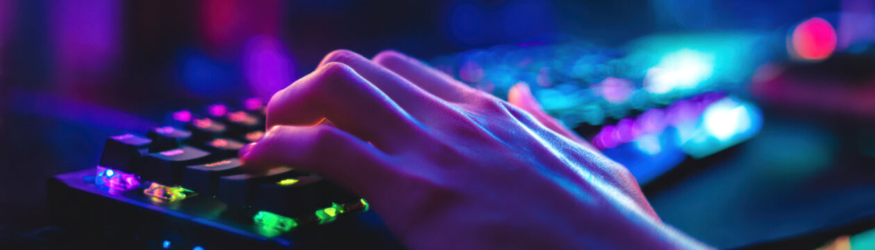 Hand typing on keyboard with colorful backlight creates authentic reality of digital interaction in vibrant low light environment